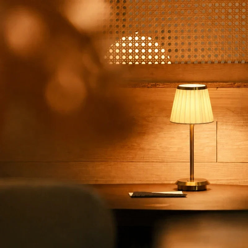 Bordslampa med veckad lampskärm och smal fot på ett bord