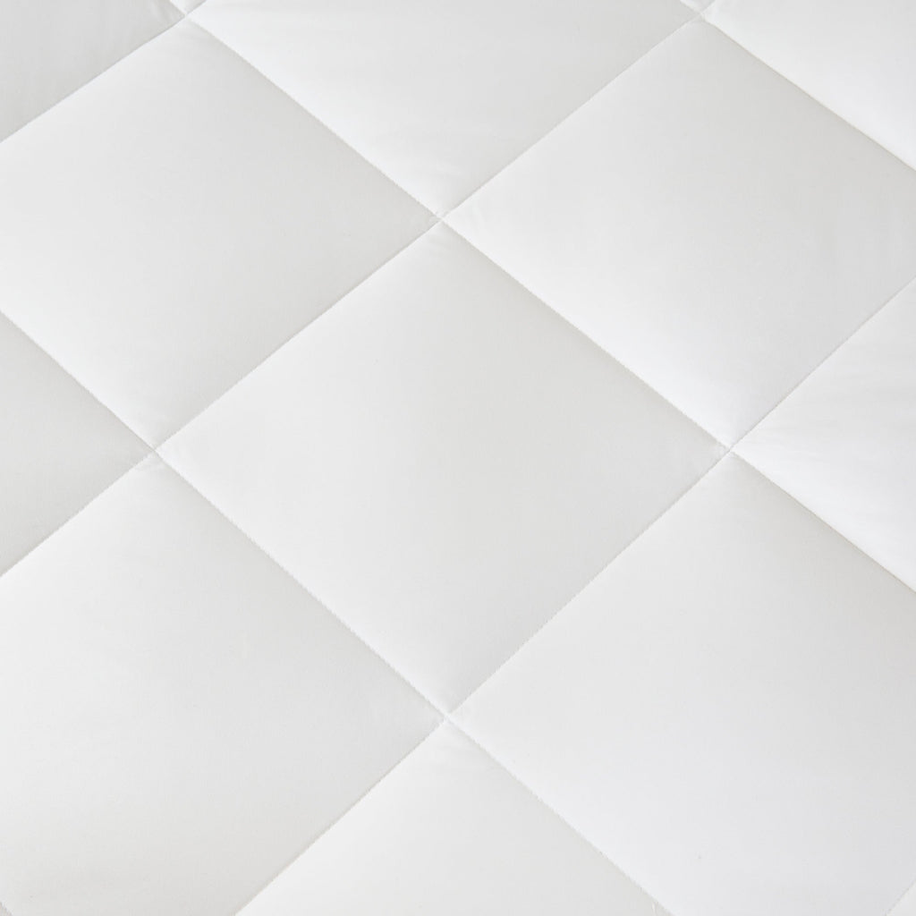 Vitt täcke med diamantmönstrad quiltning på bäddad säng
