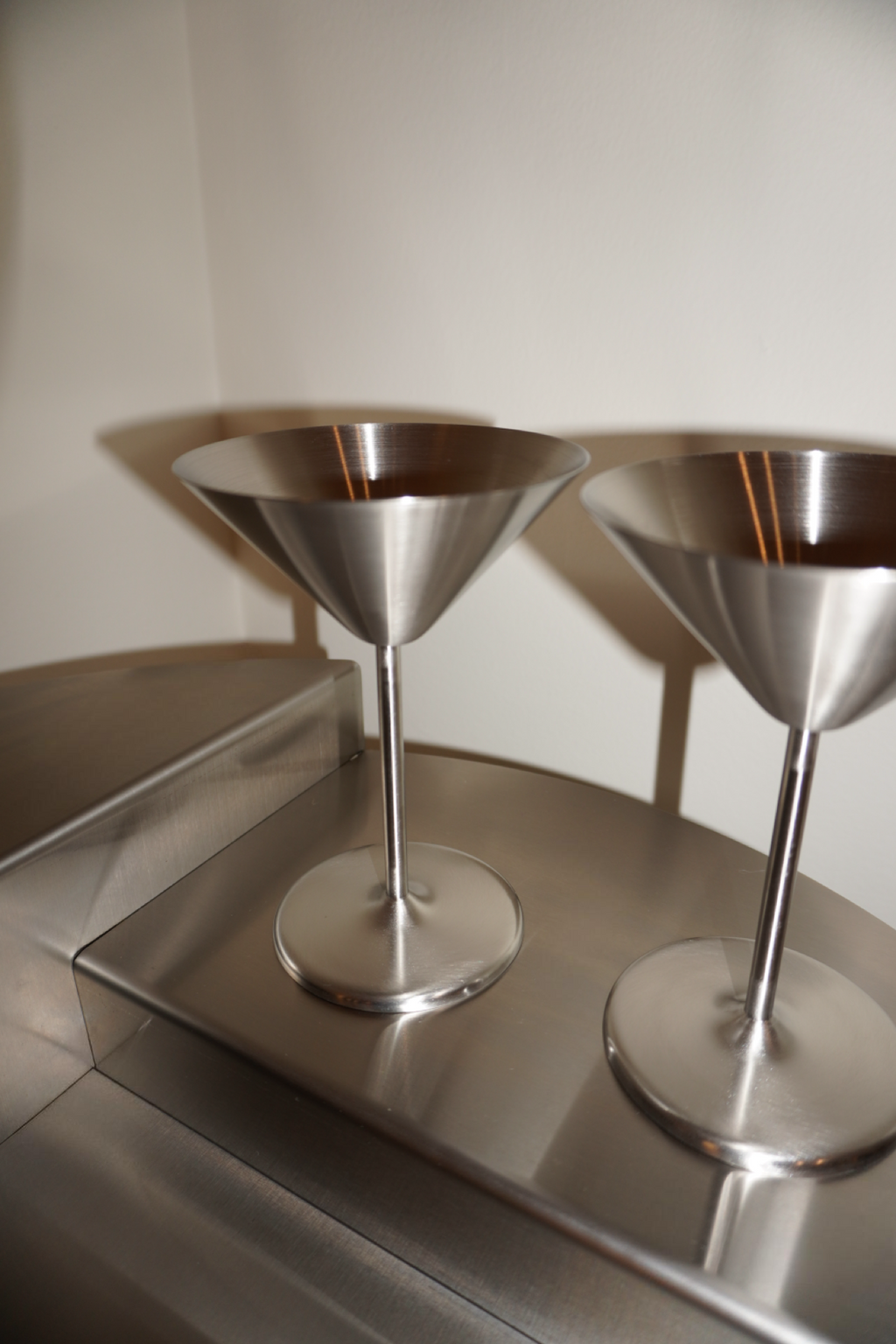 Två silverfärgade martiniglas med konformad kupa och rund fot