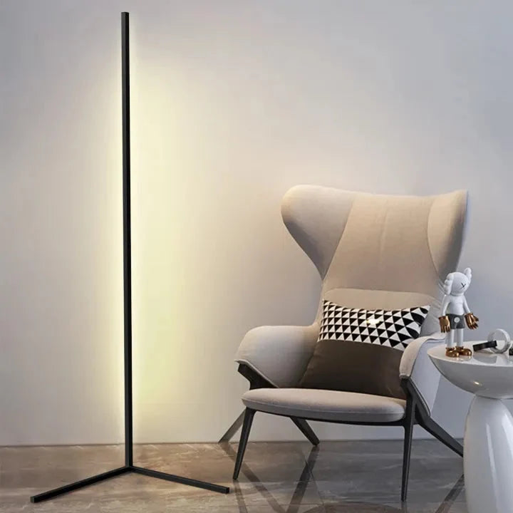 Smal dimbar LED-golvlampa placerad i ett hörn med varm belysning