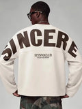 Beige oversized långärmad tröja med stor mörk textdesign på rygg och ärmar