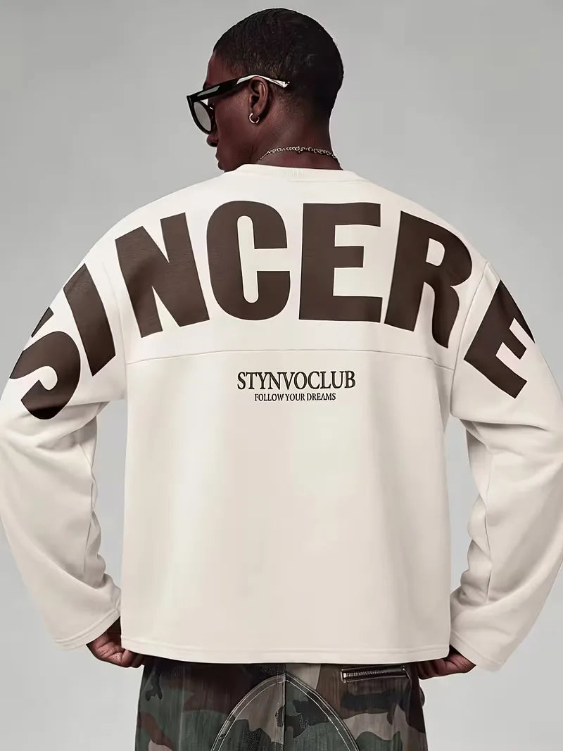 Beige oversized långärmad tröja med stor mörk textdesign på rygg och ärmar