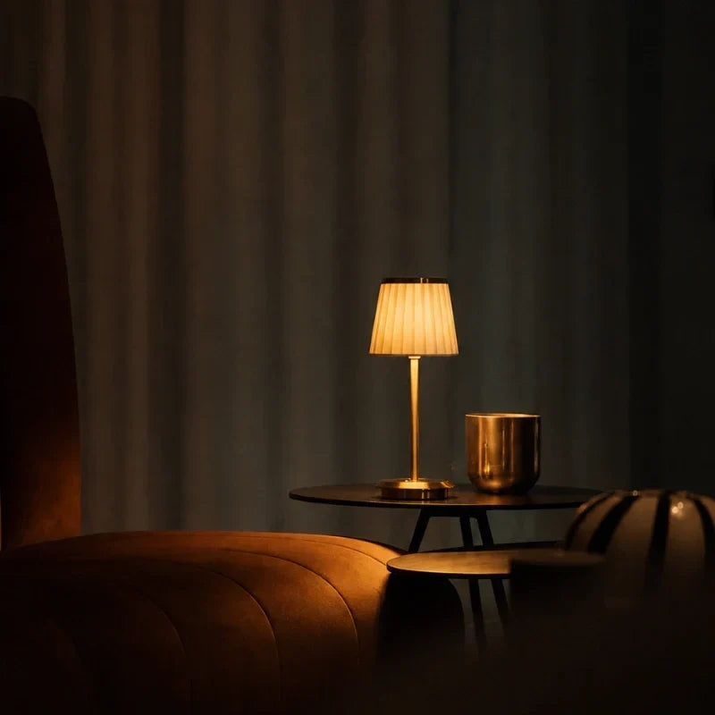 Bordslampa med veckad lampskärm och smal fot på ett bord