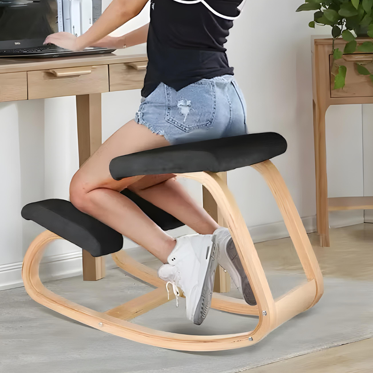 Ergonomisk knästol med svarta dynor och böjd stomme med ljus träeffekt