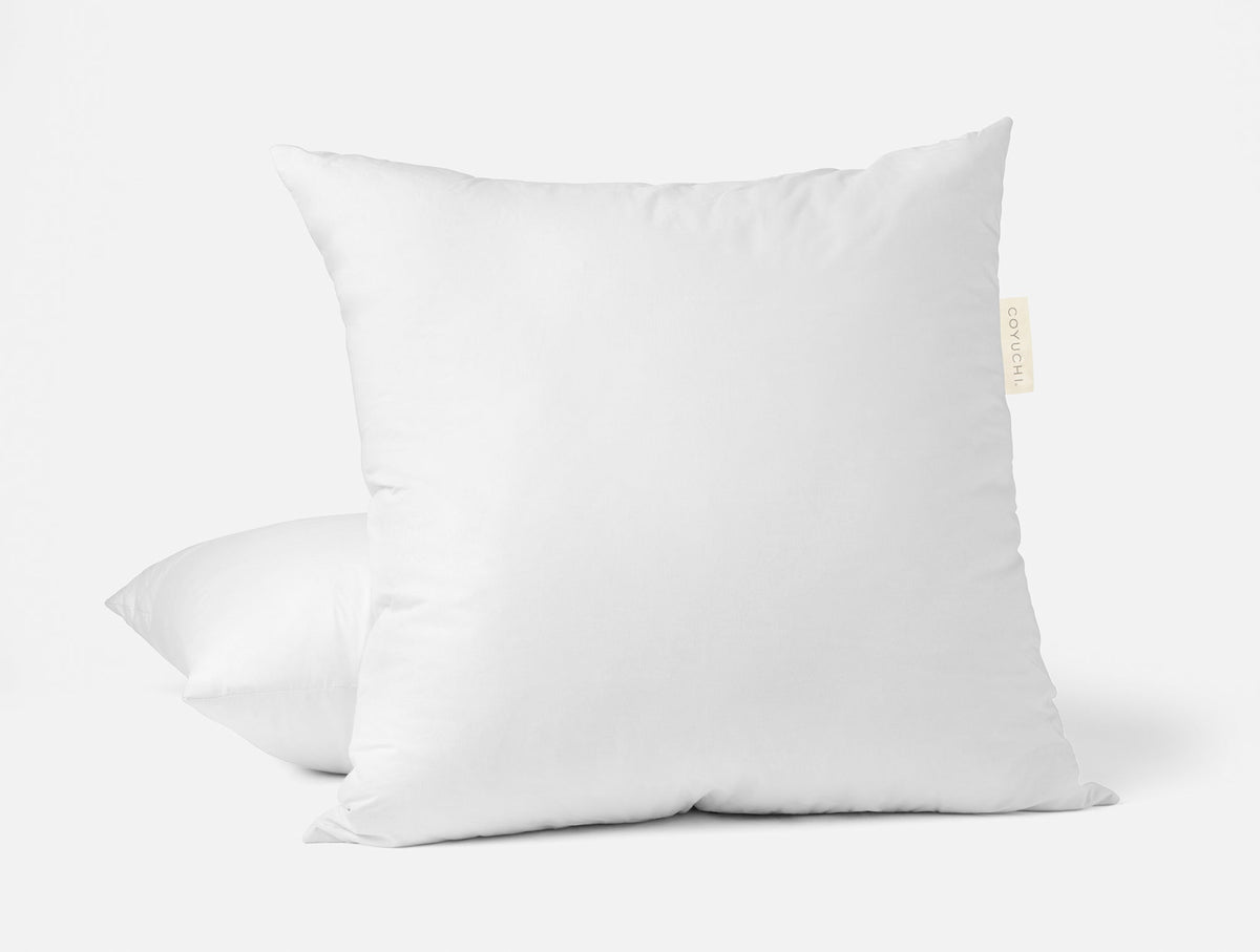 Vit dun- och fjäderkudde på en bäddad säng