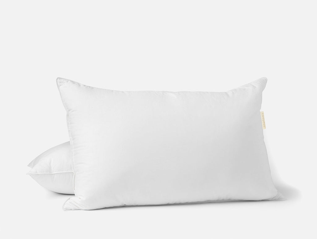 Vit dun- och fjäderkudde på en bäddad säng