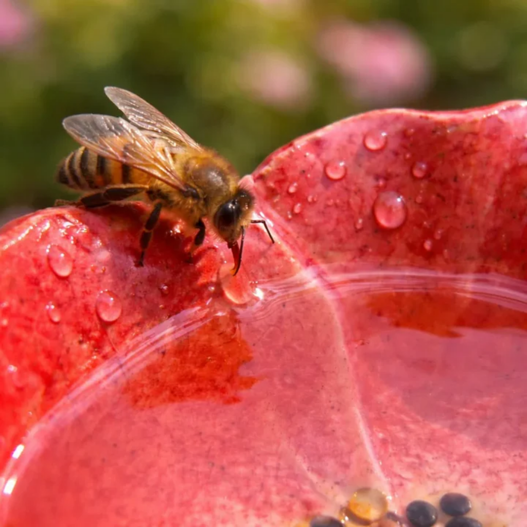 Fyra färgglada blomformade trädgårdsdekorationer på mörka stavar