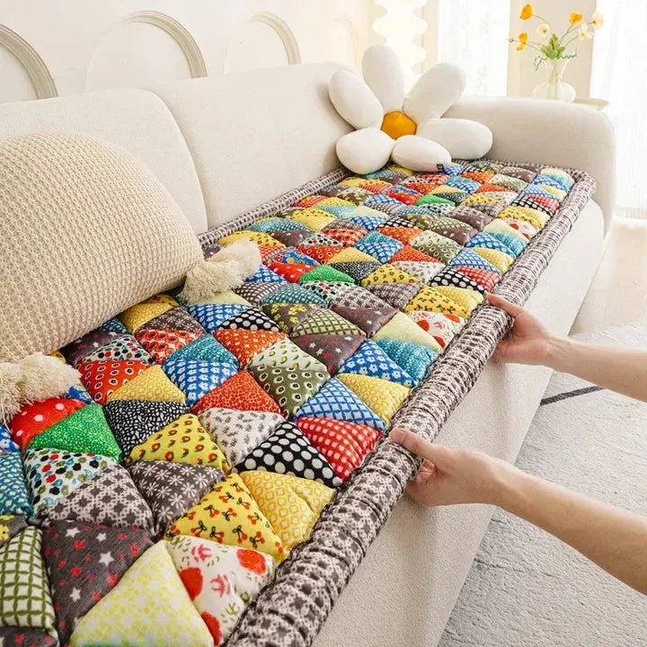 Färgglatt quiltat sofföverdrag med lapptäcksmönster och blomformad kudde