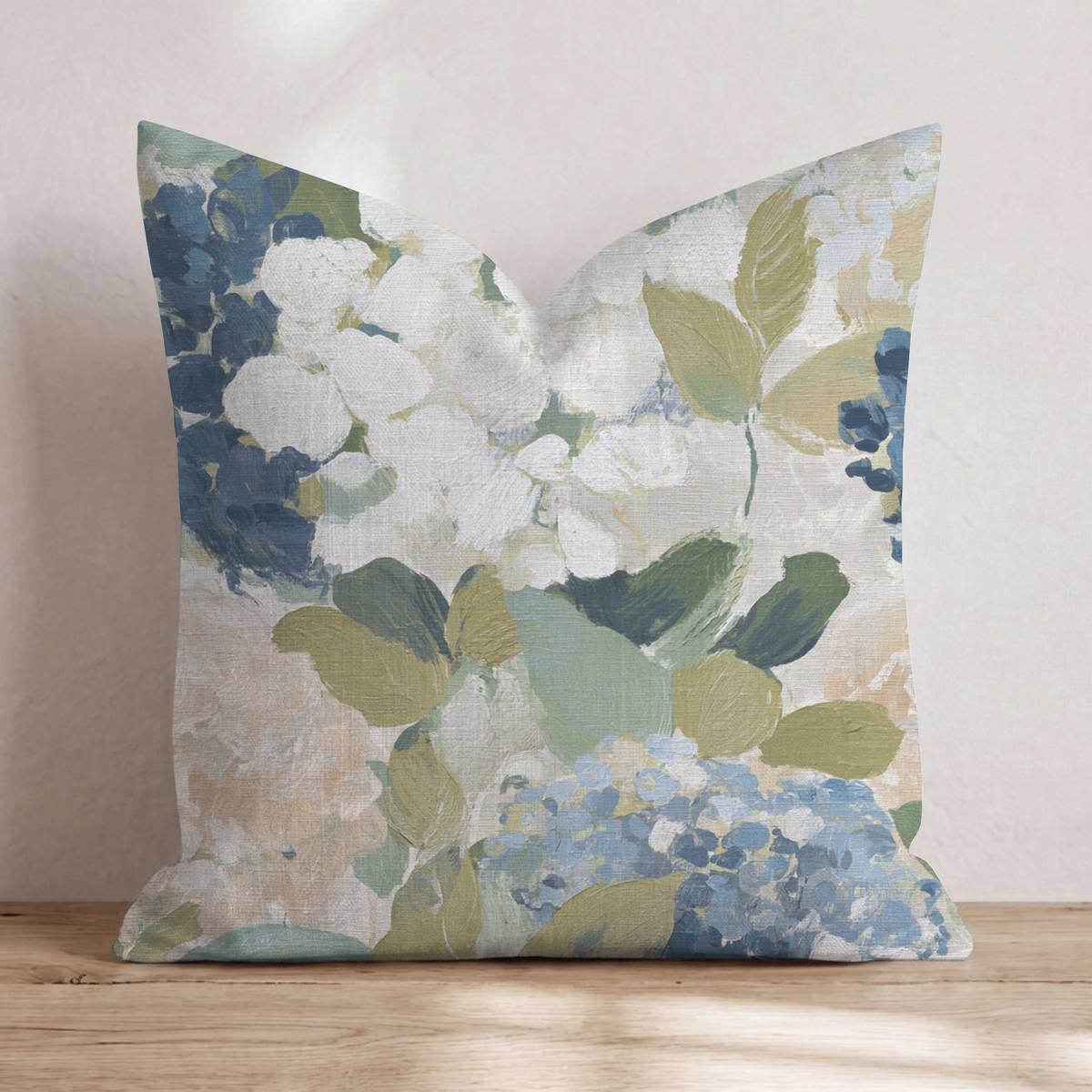 Beige prydnadskudde med blått och grönt blommönster i en soffa