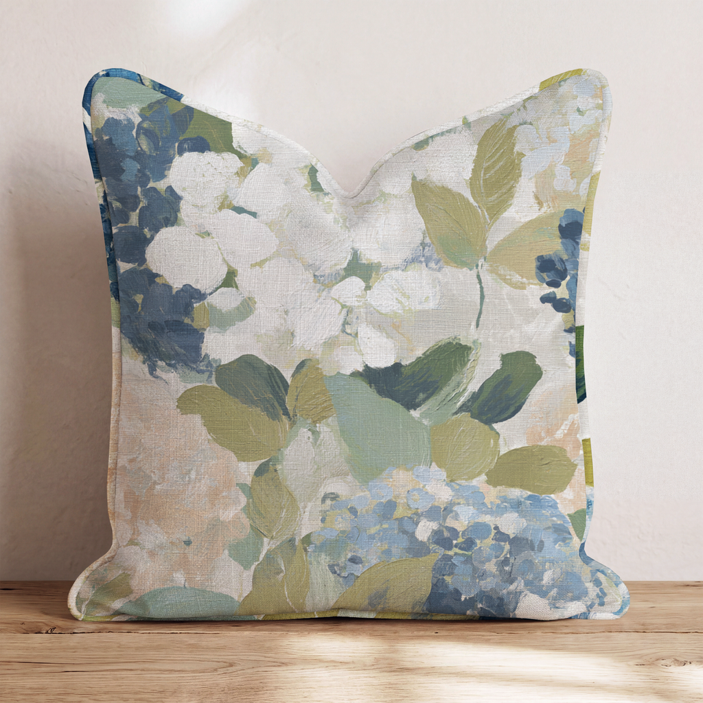 Beige prydnadskudde med blått och grönt blommönster i en soffa
