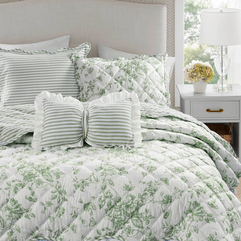 Quiltset med blommigt mönster, volangkant och dekorativ kudde på bäddad säng