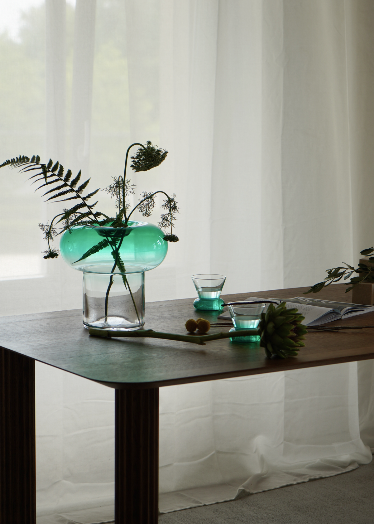 Grön rund glasvas med transparent fot för snittblommor