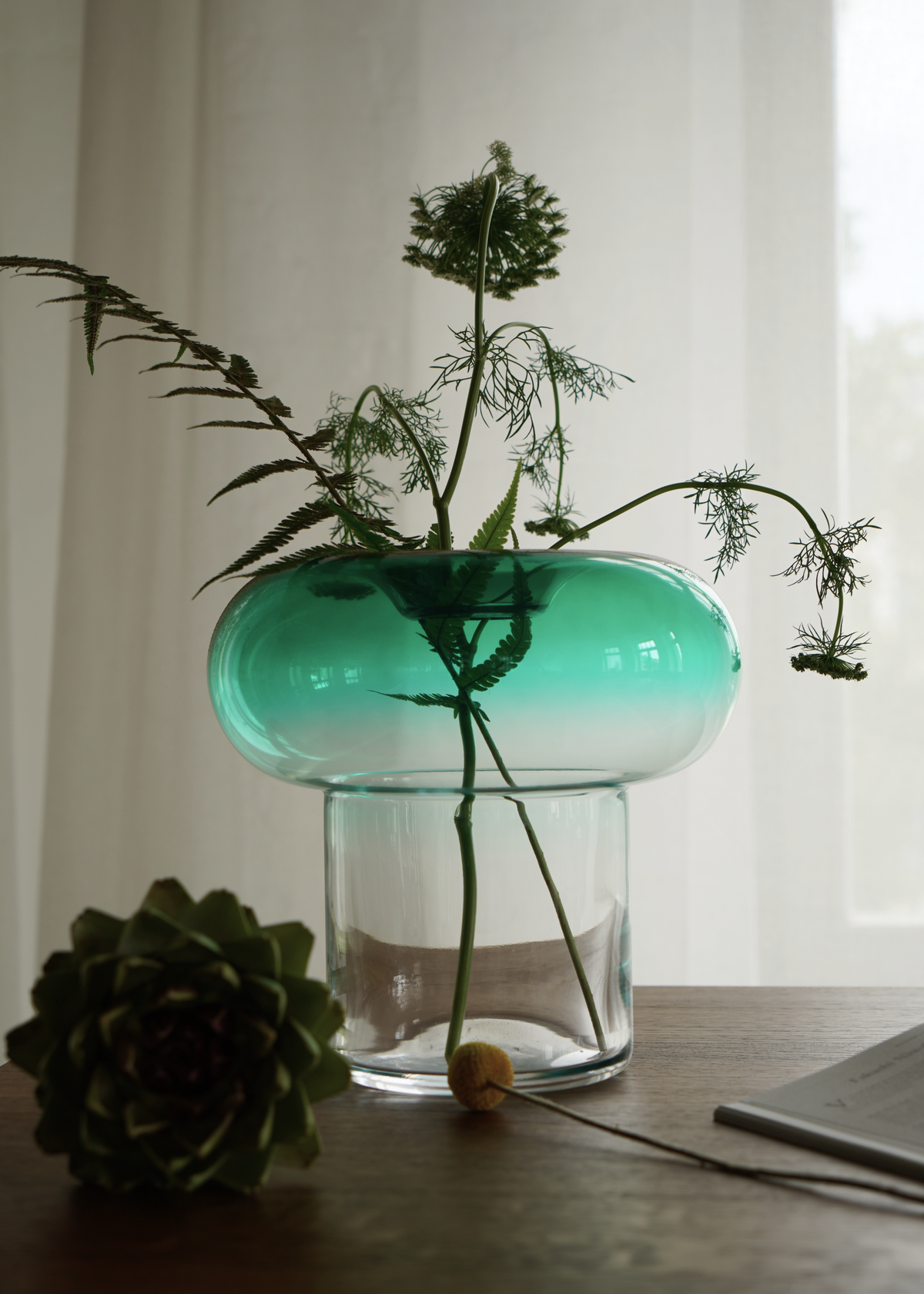 Grön rund glasvas med transparent fot för snittblommor