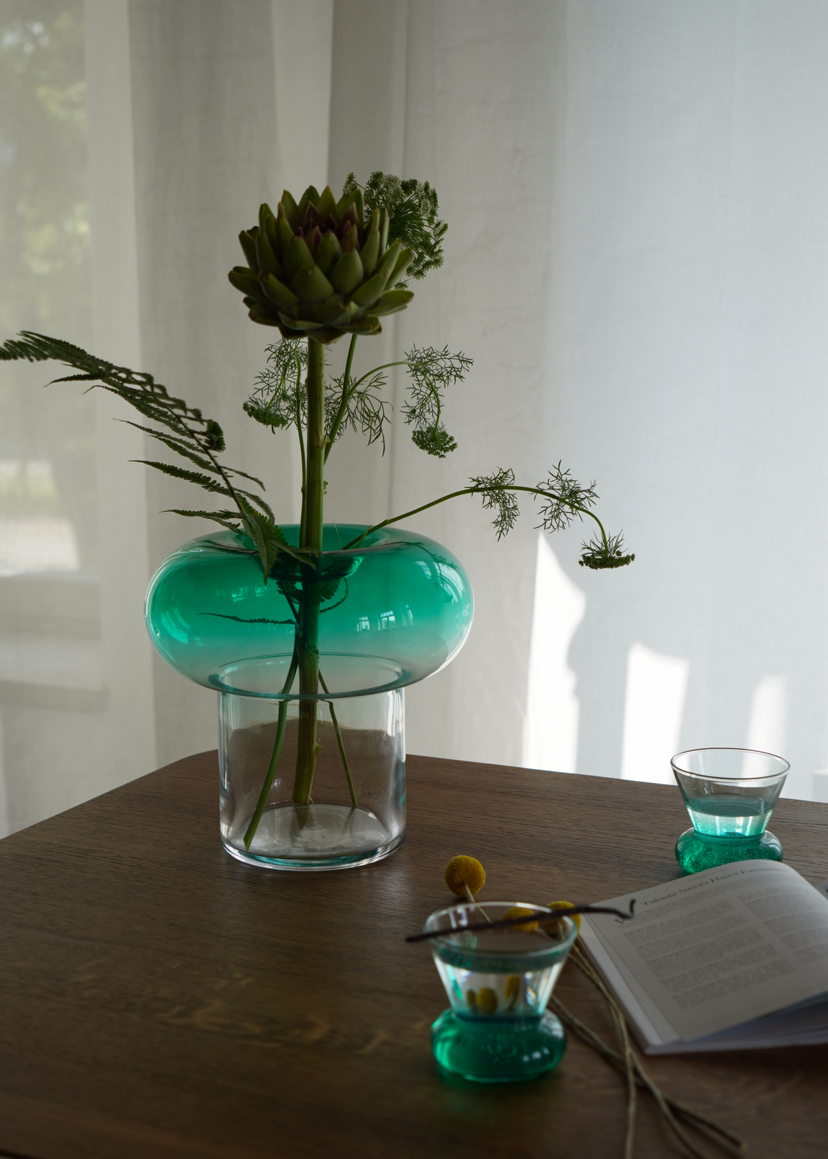 Grön rund glasvas med transparent fot för snittblommor