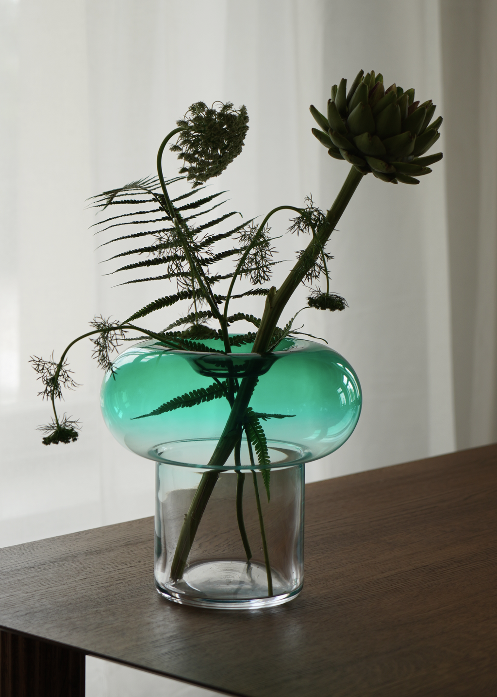 Grön rund glasvas med transparent fot för snittblommor