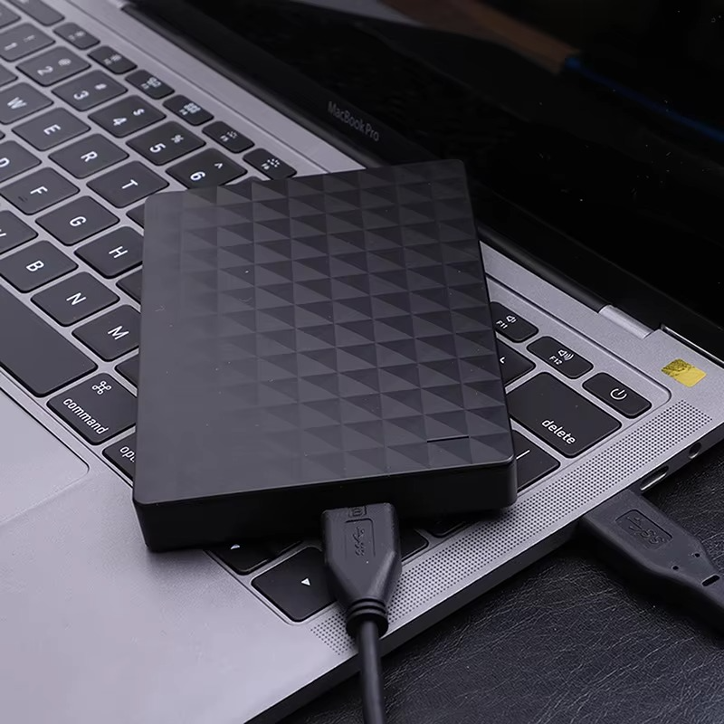 Svart extern hårddisk med geometriskt mönster och USB-kabel