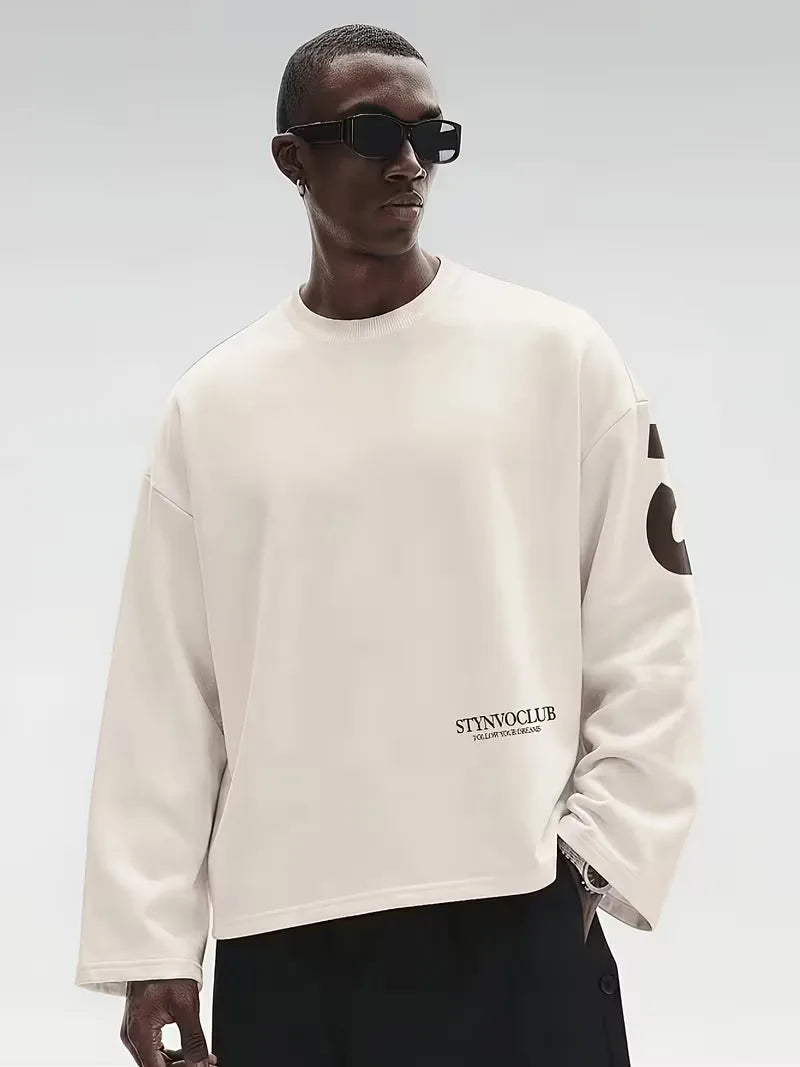 Beige oversized långärmad tröja med stor mörk textdesign på rygg och ärmar