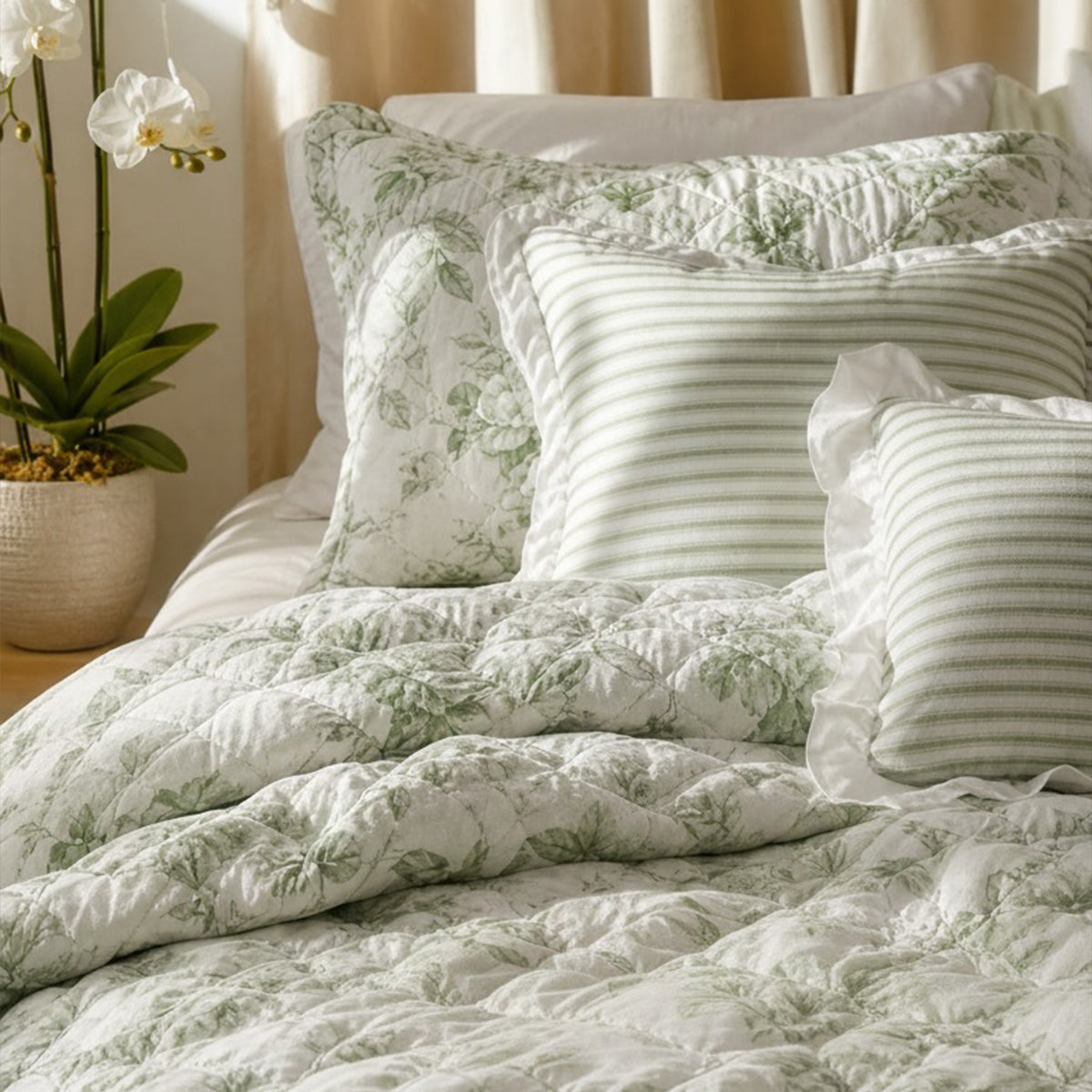 Quiltset med blommigt mönster, volangkant och dekorativ kudde på bäddad säng