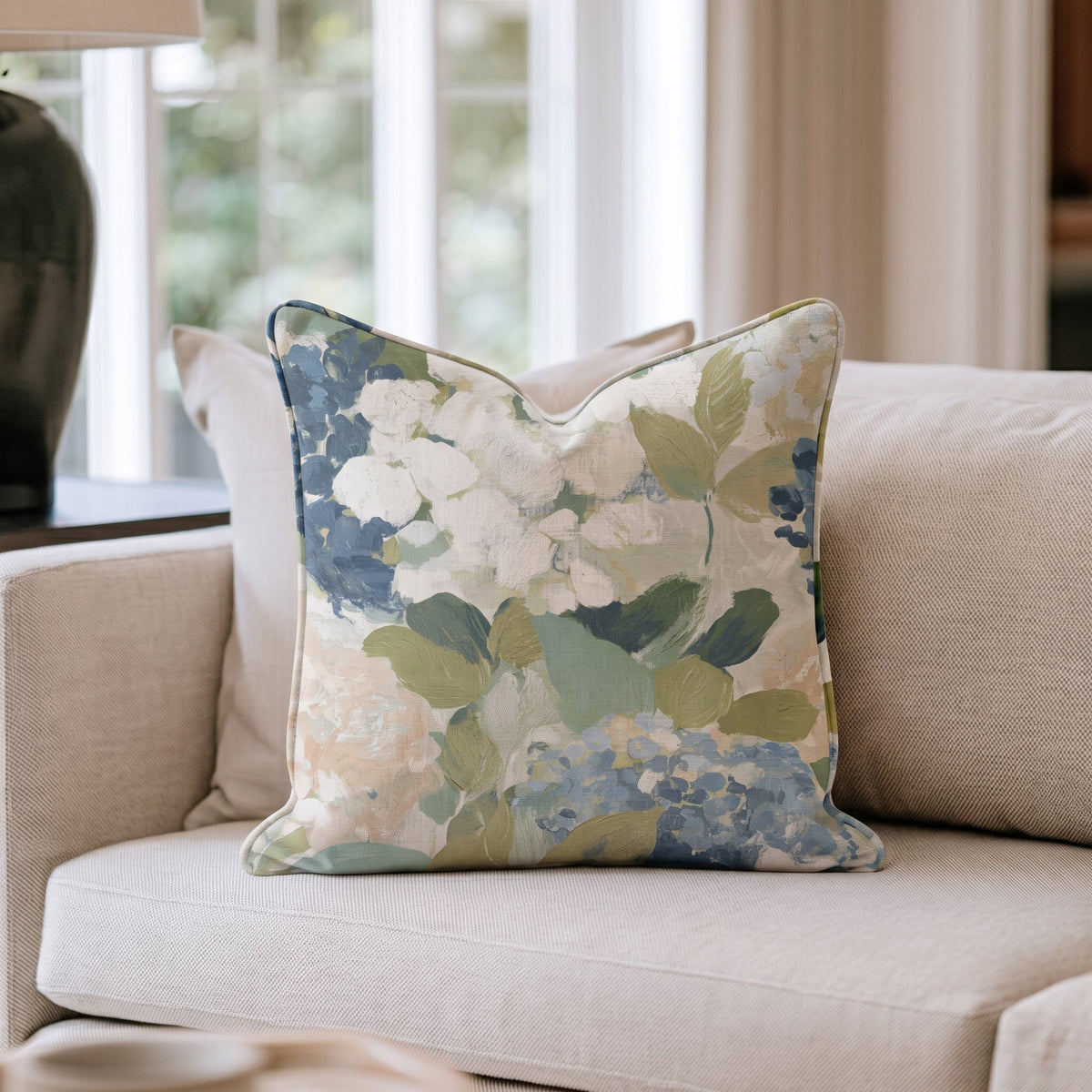 Beige prydnadskudde med blått och grönt blommönster i en soffa