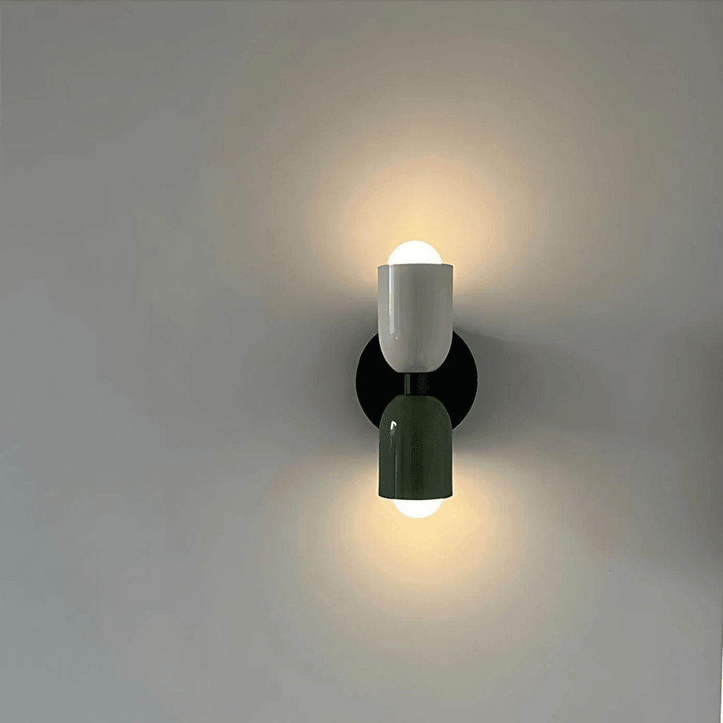 Vägglampa med två cylindriska delar och rund svart väggplatta