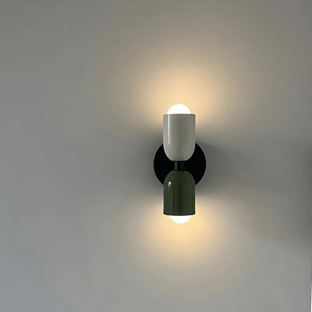 Vägglampa med två cylindriska delar och rund svart väggplatta