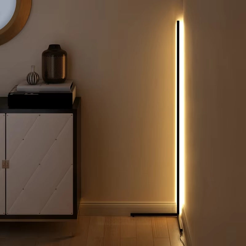 Smal dimbar LED-golvlampa placerad i ett hörn med varm belysning