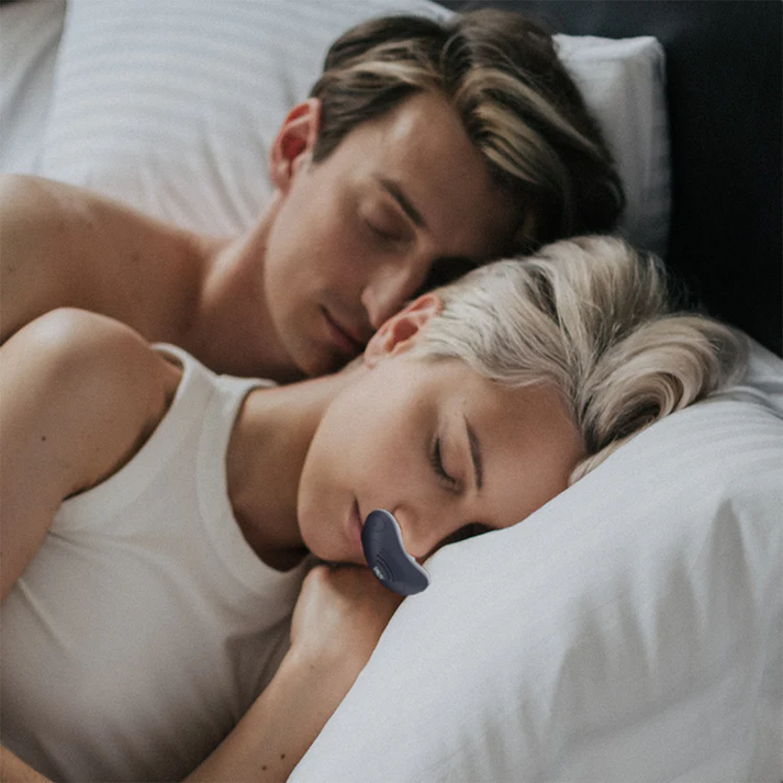 Kompakt CPAP-enhet med två vita näsdelar, ventilationsöppningar, strömbrytare och USB-port