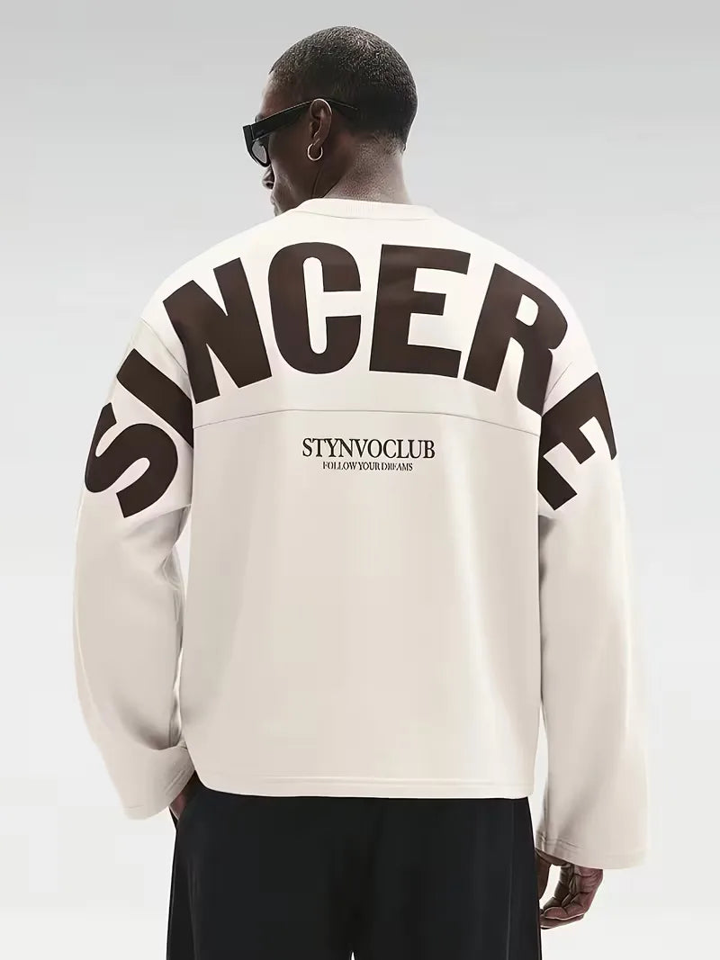 Beige oversized långärmad tröja med stor mörk textdesign på rygg och ärmar