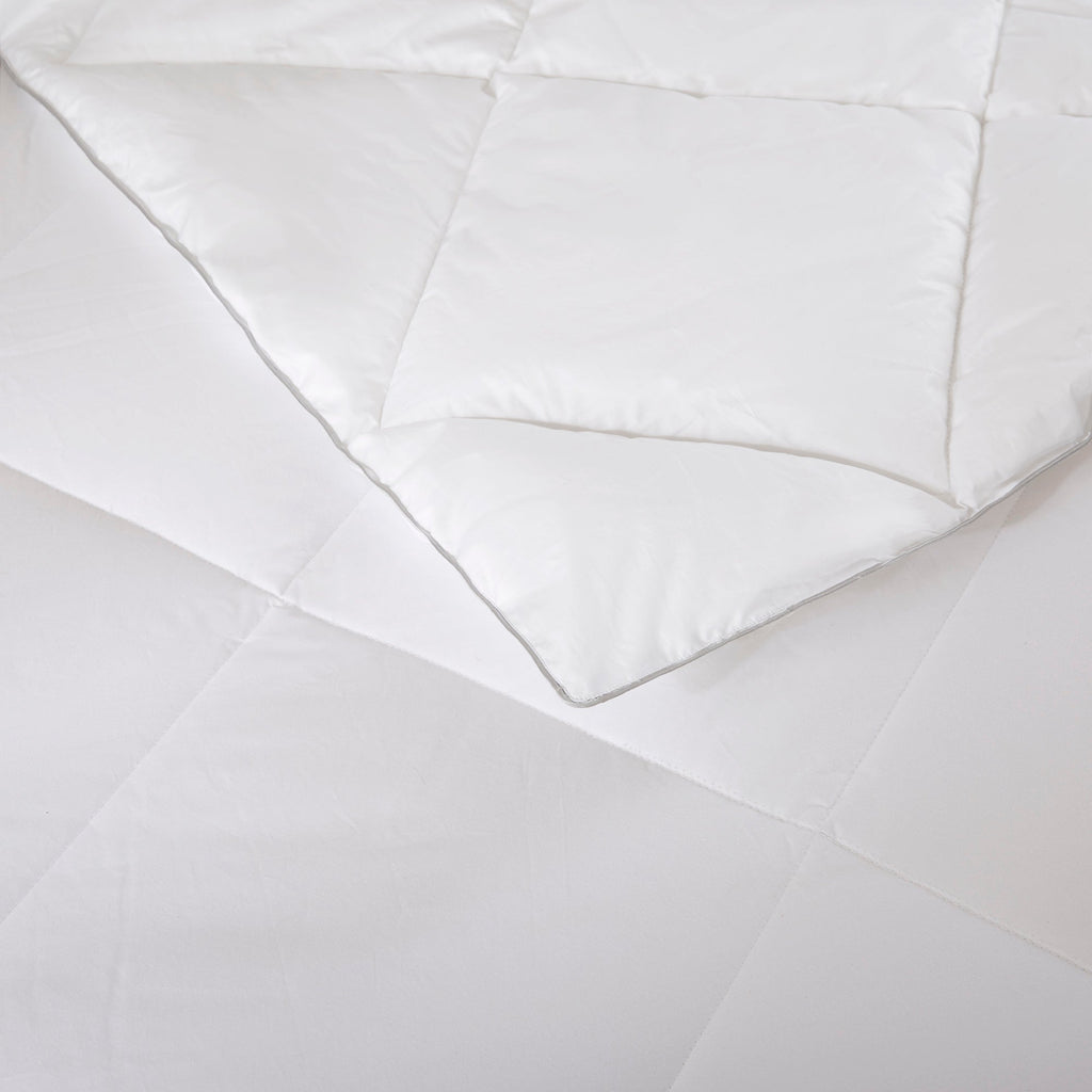 Vitt täcke med diamantmönstrad quiltning på bäddad säng