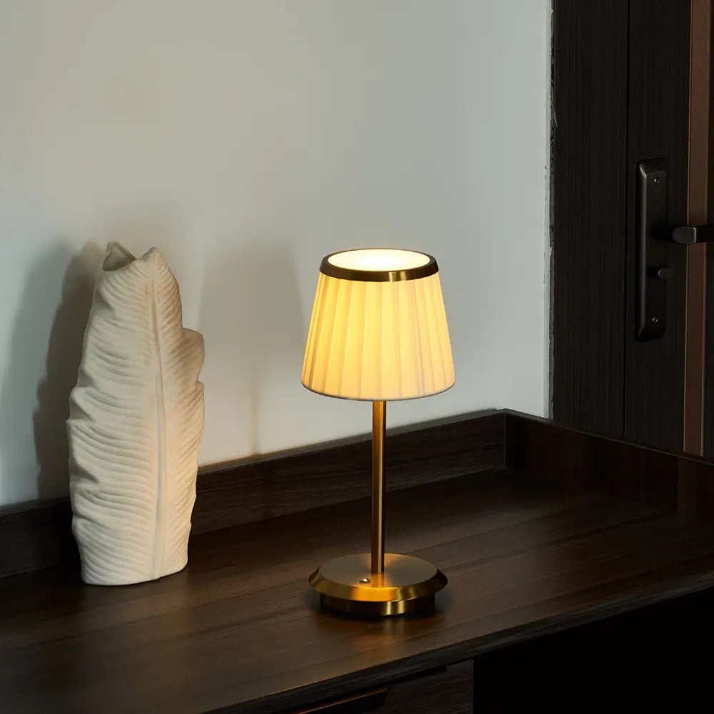 Bordslampa med veckad lampskärm och smal fot på ett bord