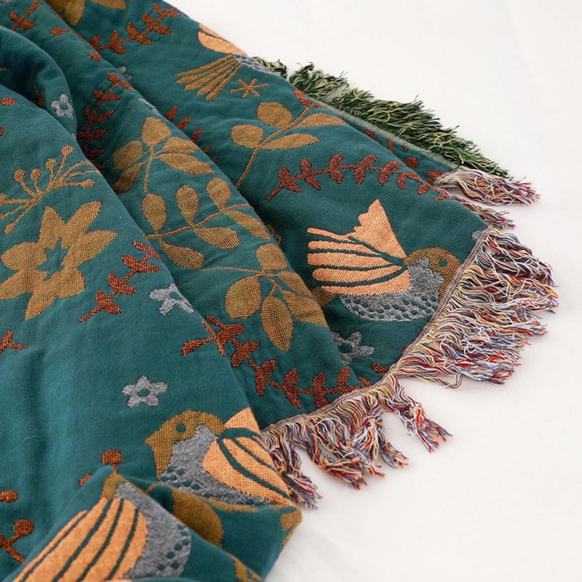 Vändbart blågrönt överkast med blommor, fåglar och fransad kant